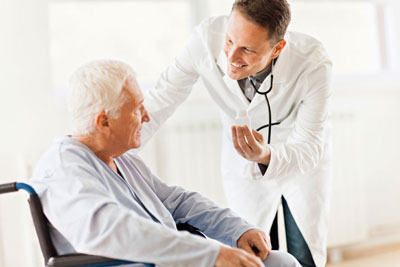 A doctor speaking with an elderly man in a wheelchair