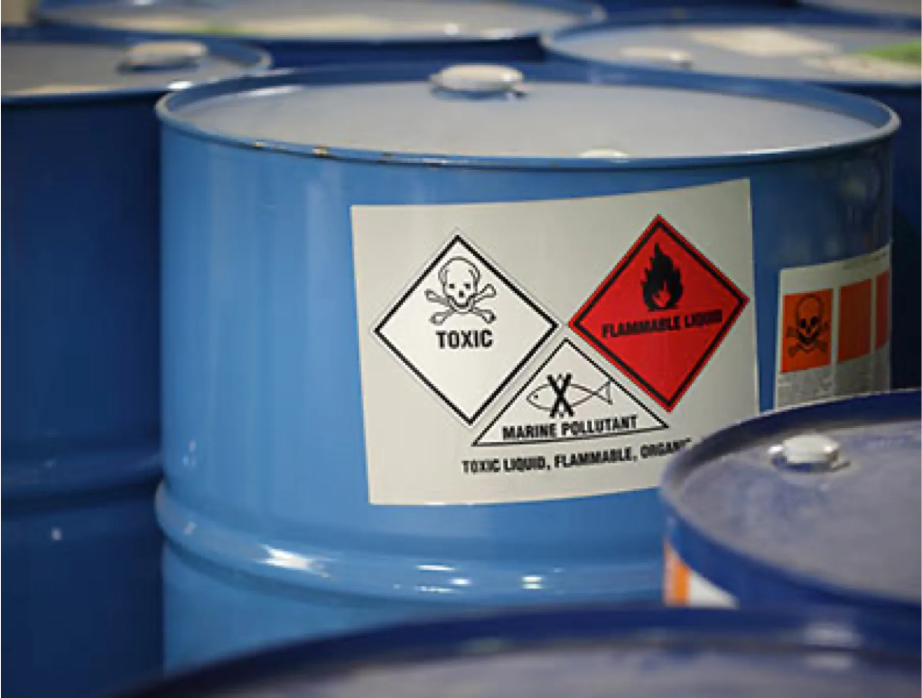 A blue barrel with toxic and flammable warning labels on it.